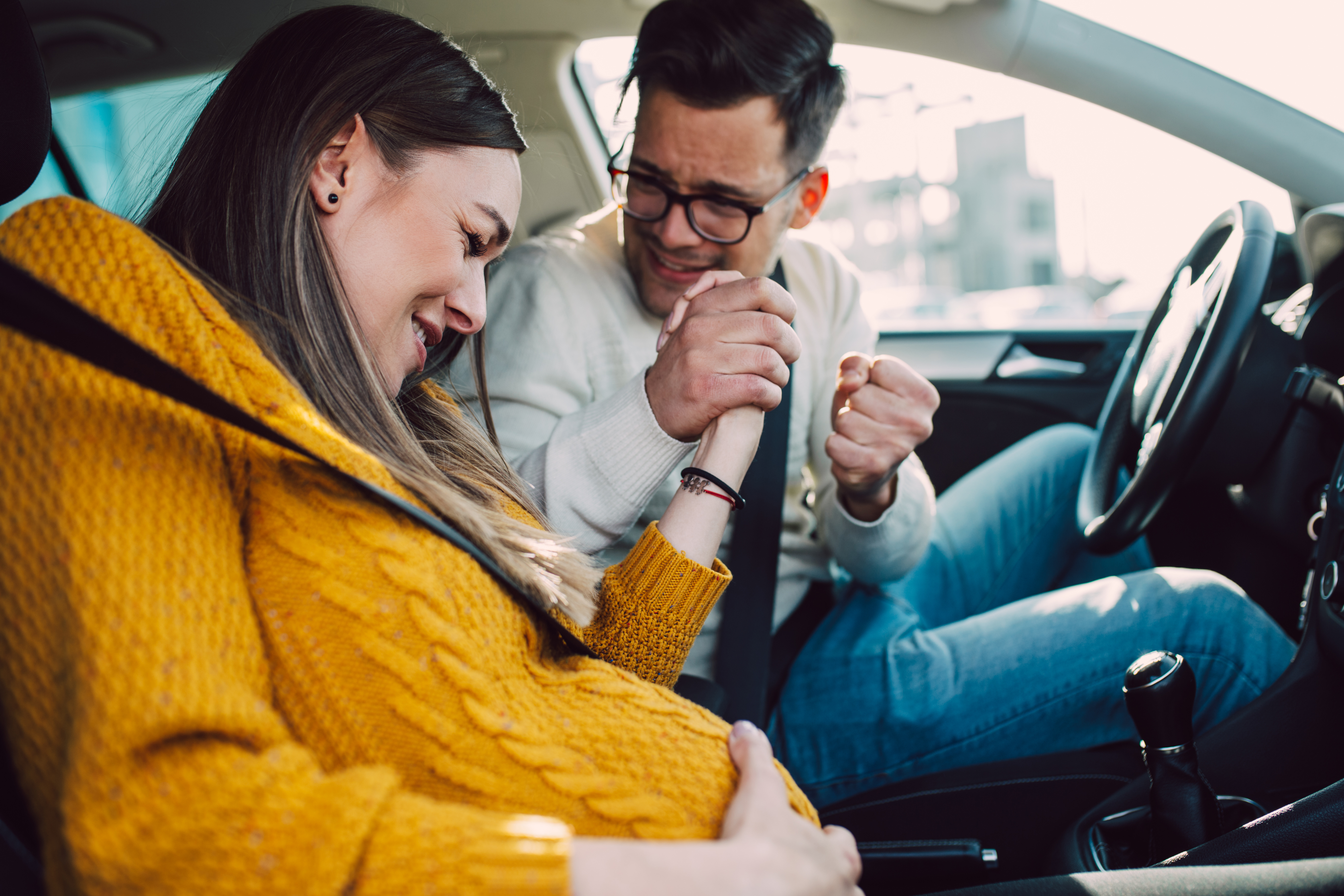 Pregnant woman starting to feel pain and contractions while her worried husband driving a car | Source: Shutterstock