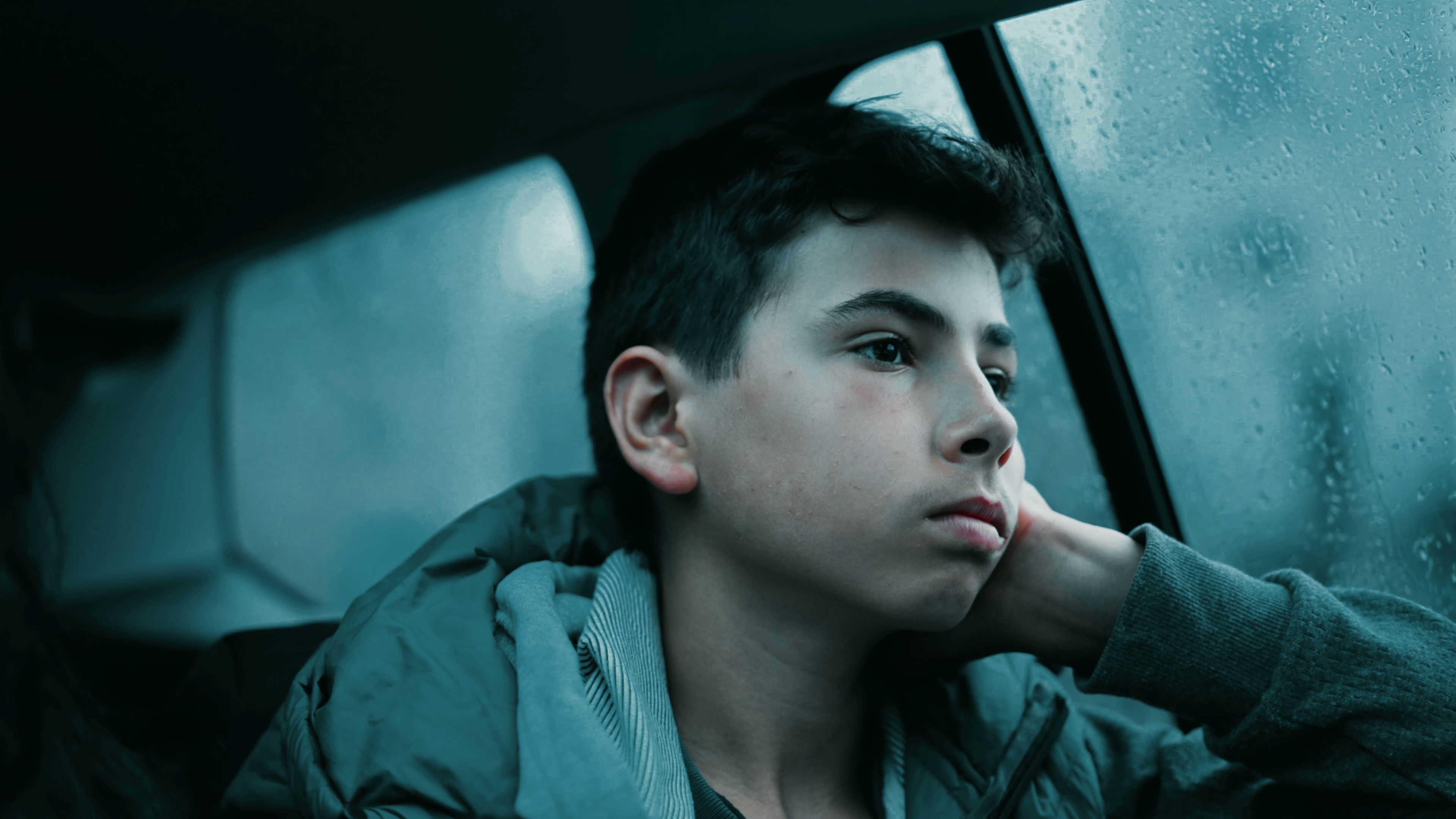 Sad young boy is sitting near the window in the car | Source: Shutterstock.com