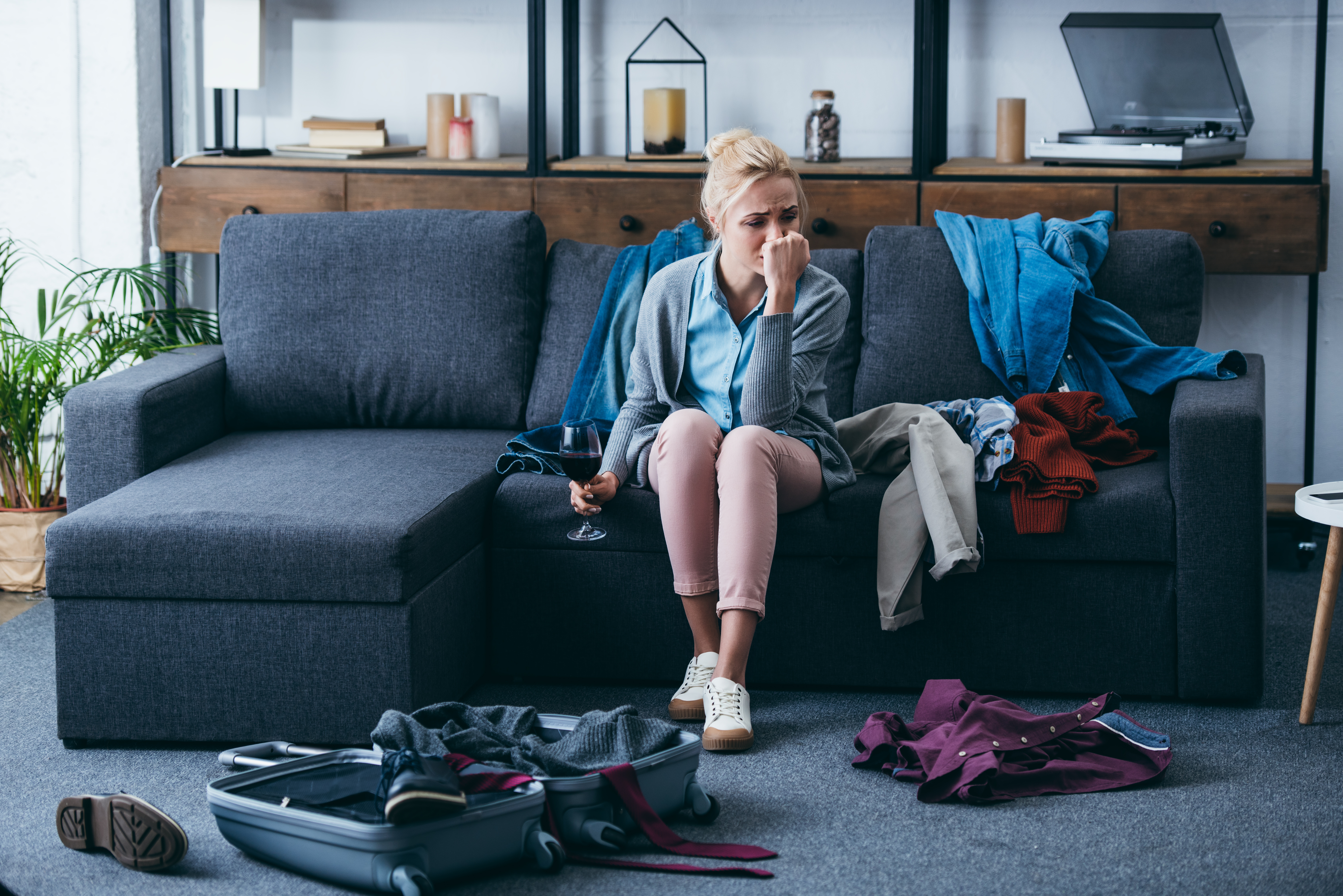 Depressed woman sitting on sofa and crying while packing | Source: Shutterstock