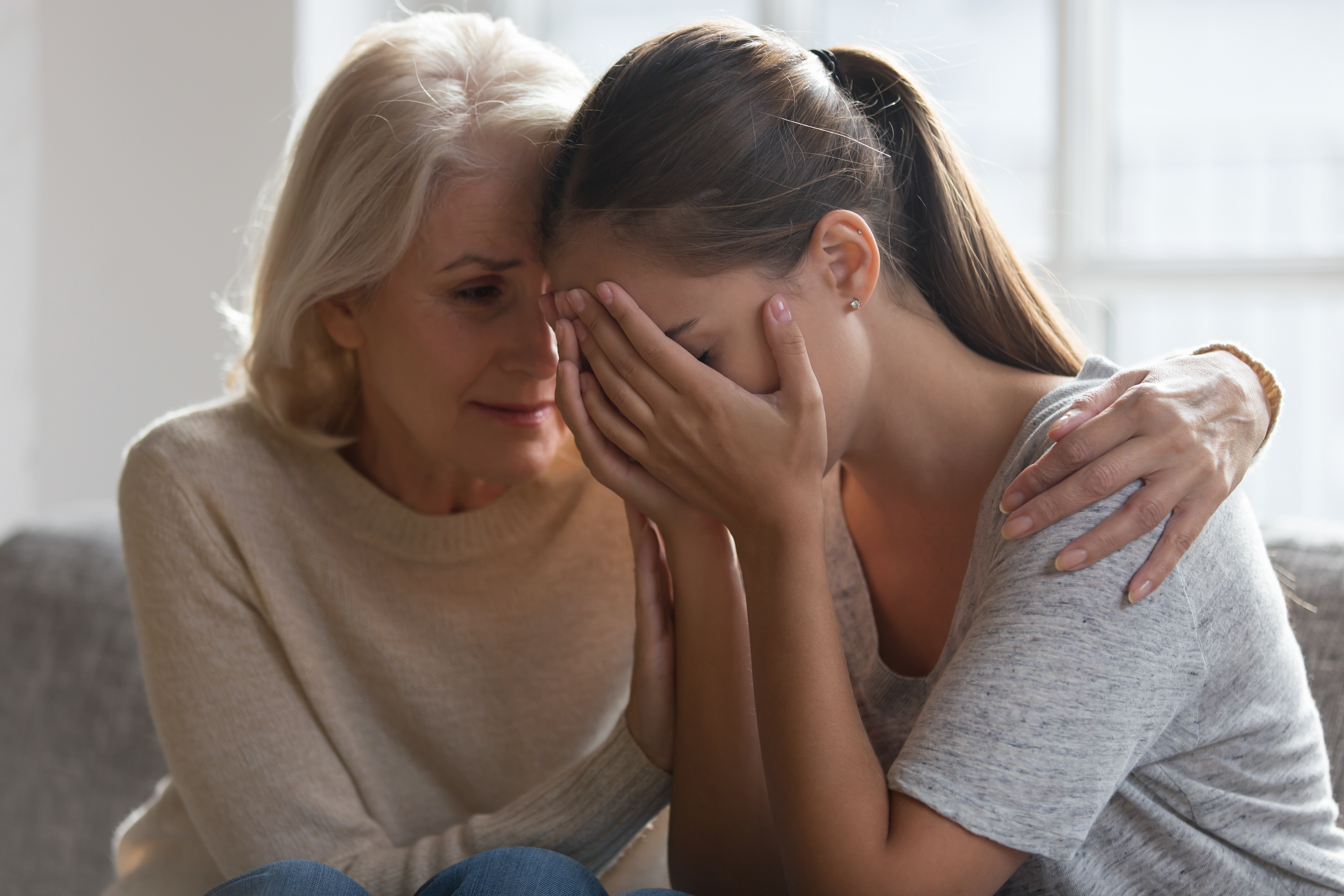 Worried aged mother embracing comforting grown up daughter | Source: Shutterstock